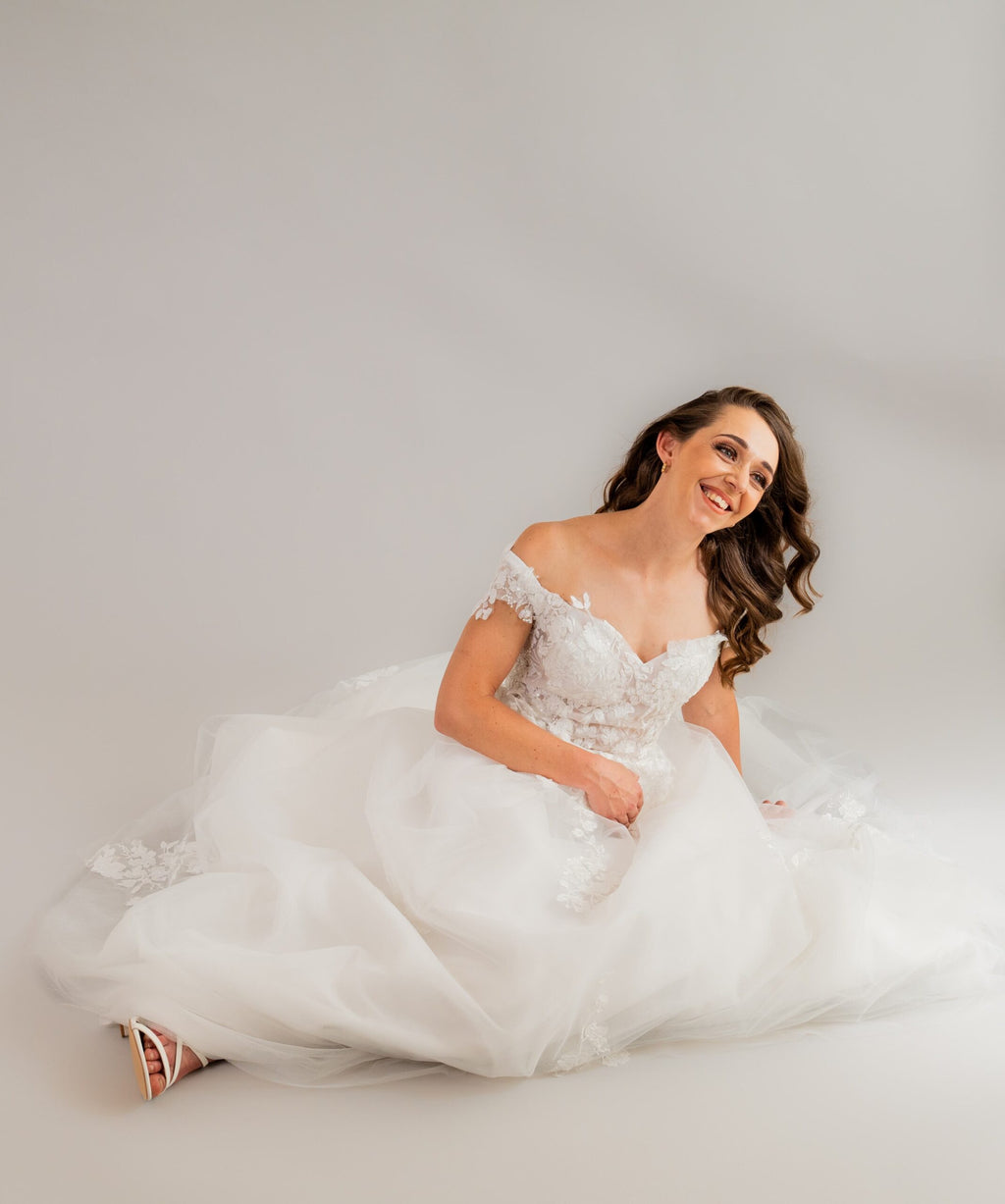 Seated pose showcasing delicate applique details and luxurious tulle on wedding gown