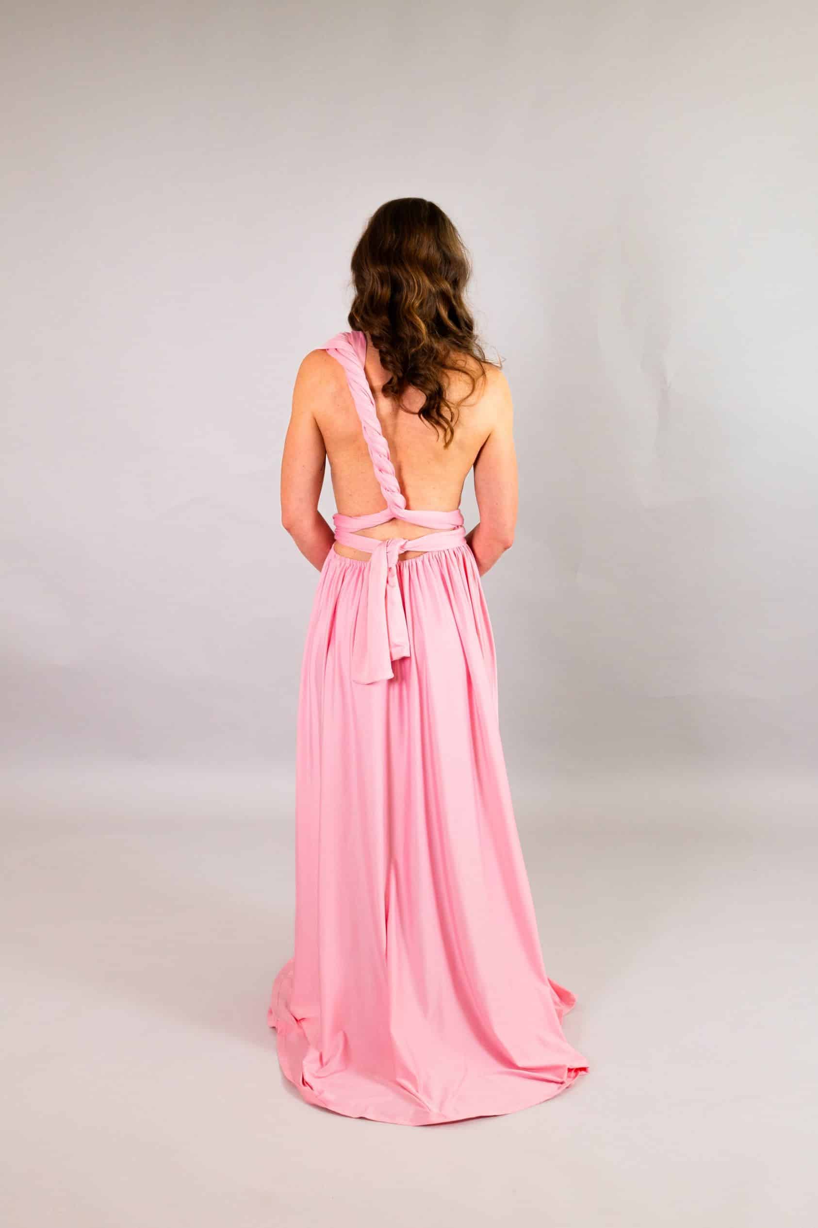 Open back of baby pink infinity dress with braided shoulder strap and bow-tied waist straps
