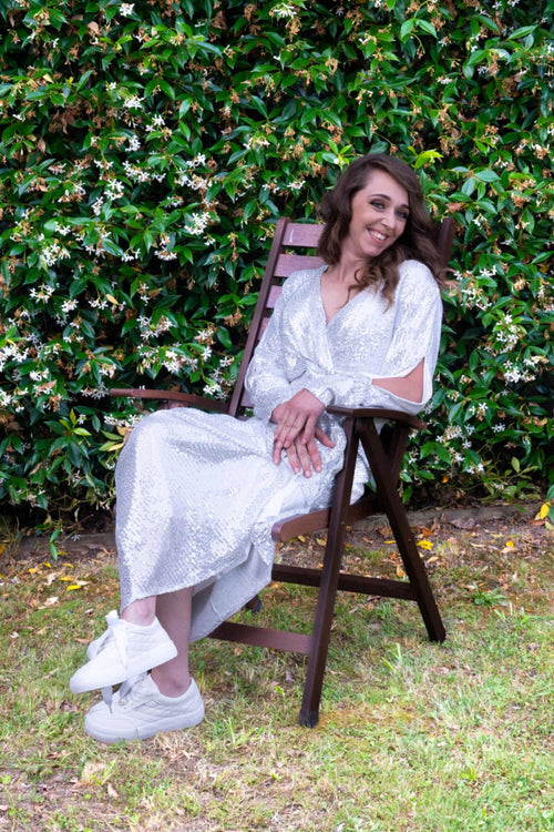 Bride in sequin gown wearing bridal white sneakers, seated outdoors – Art Kollocsion Auckland