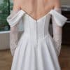 off-shoulder wedding dress features a softly draped neckline with delicate, gathered sleeves that highlight the shoulders beautifully. The structured corset bodice creates a sculpted, feminine silhouette, offering both support and a flattering shape.